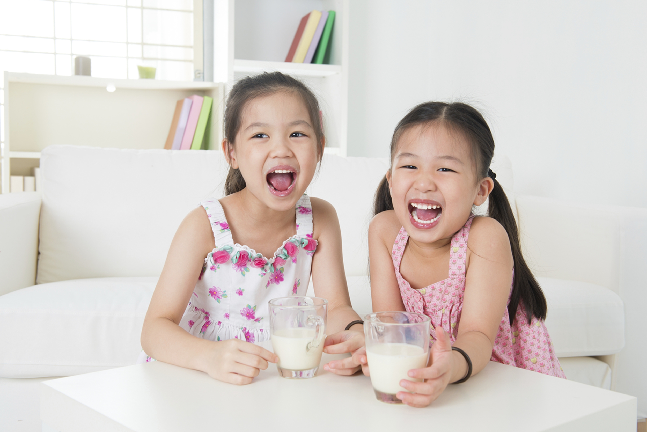 Children drinking milk. Asian family at home. Beautiful sister drinks milk together.